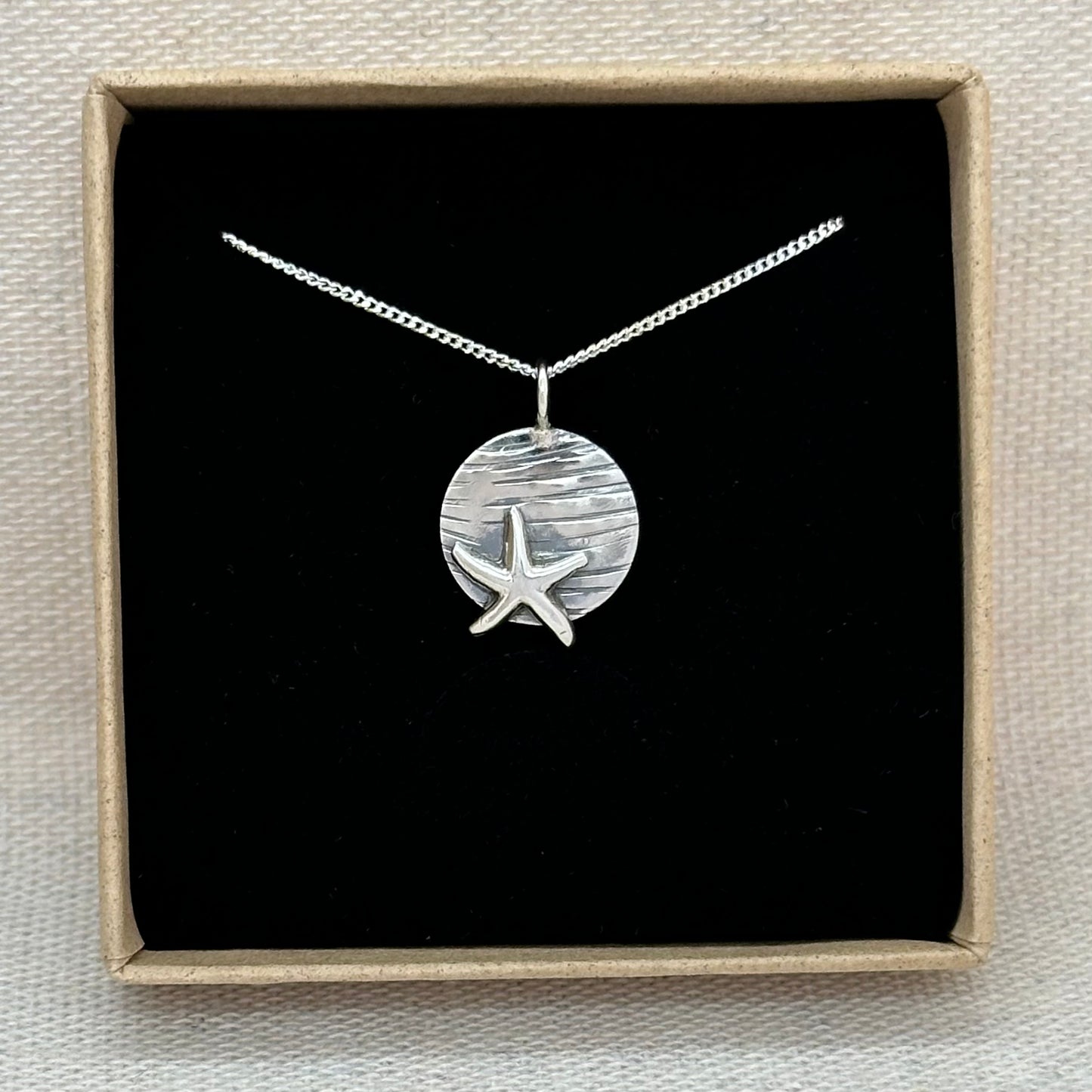 A sterling silver starfish pendant in an Impressums Jewellery branded gift box, ready for gifting