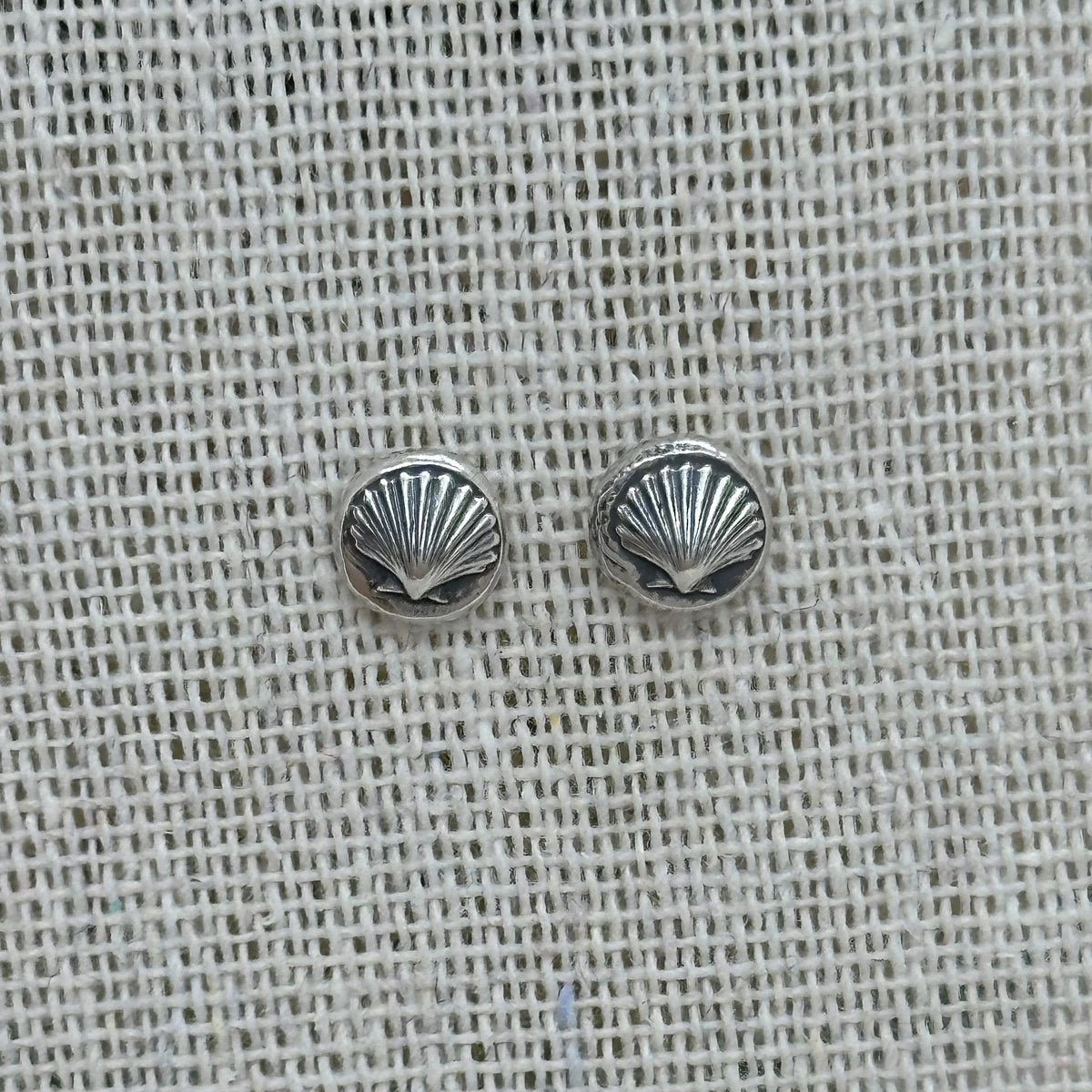Close-up of the silver shell pebble earrings, highlighting the embossed details and patinated finish.