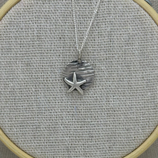 Handmade sterling silver starfish pendant with a textured coin background, displayed on an 18-inch silver curb chain