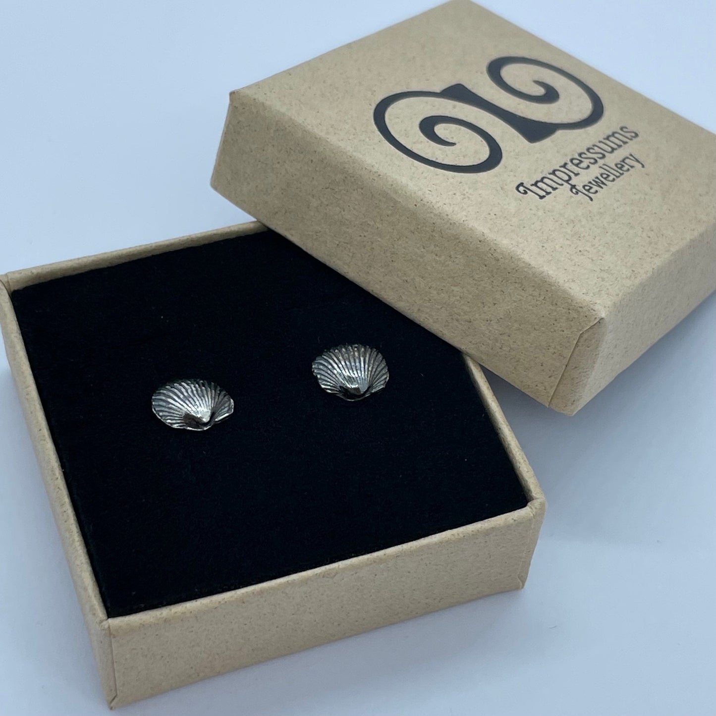 A pair of sterling silver cockle shell earrings in an Impressums Jewellery branded gift box, ready for gifting.