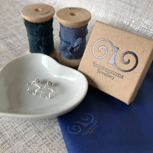 Side view of the earrings, showing the lightweight open star shape and polished silver ear posts.