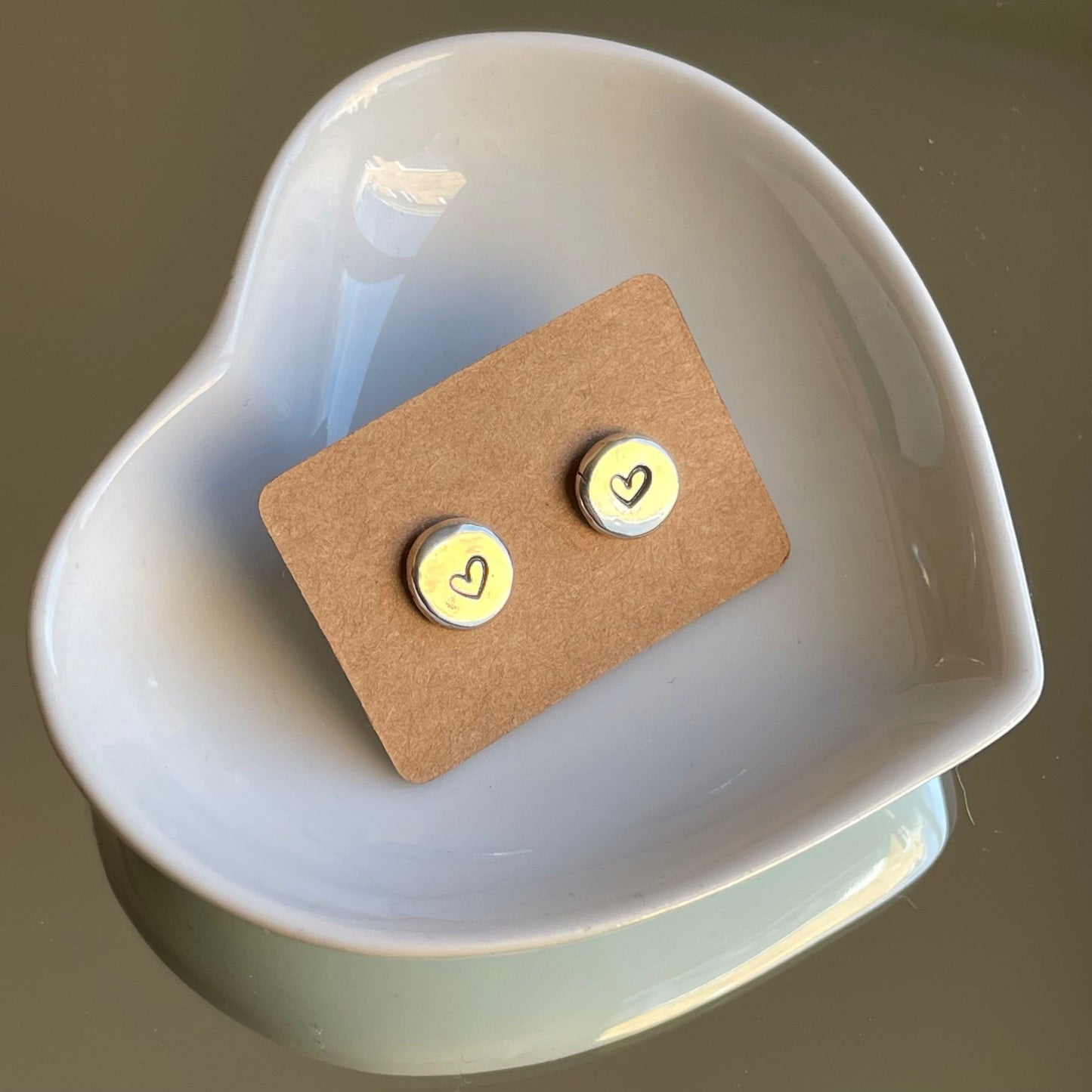 "Detailed shot of the heart-stamped design on recycled silver pebble studs, showcasing the textured and unique surface."