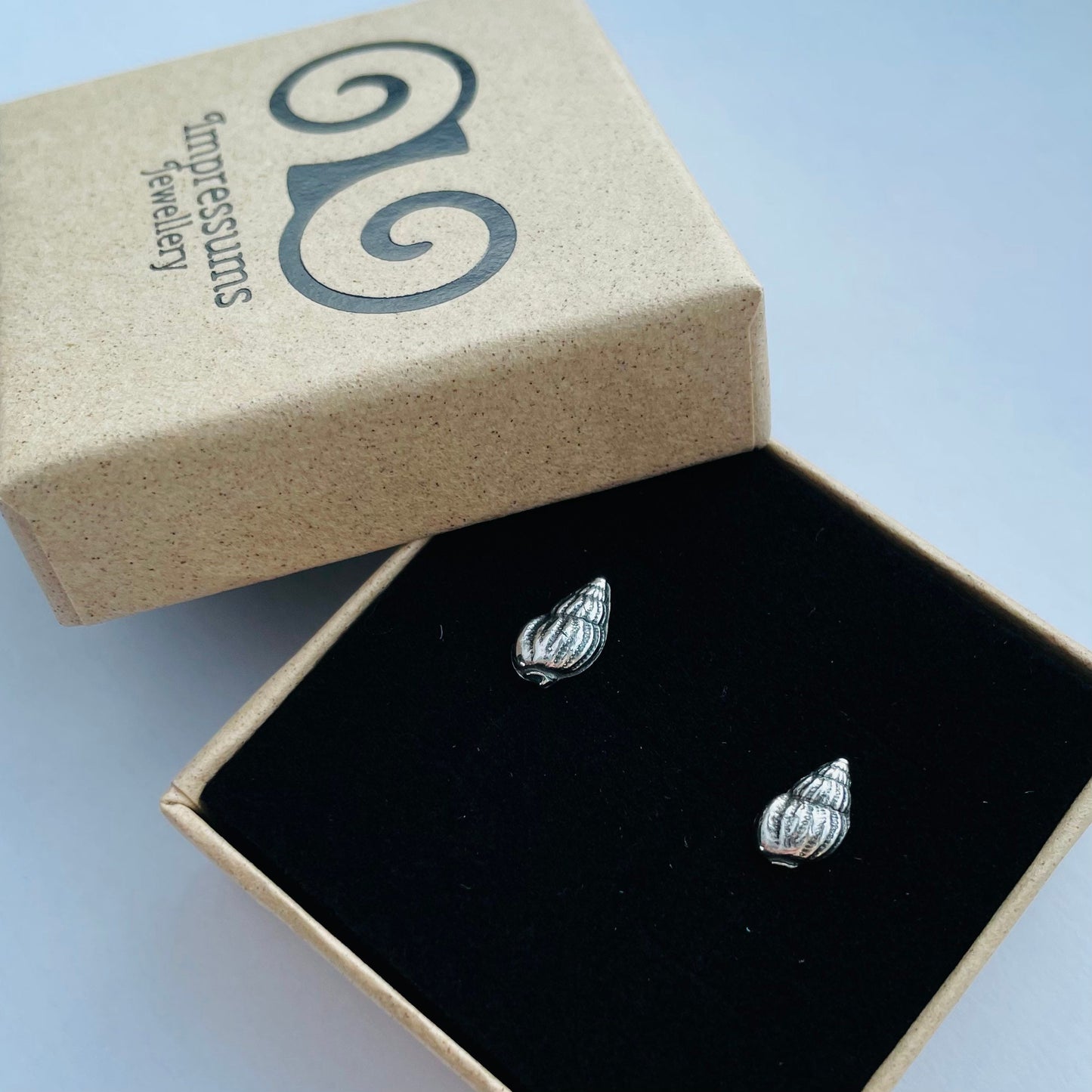 Side view of the earrings, highlighting their organic shell shape and high-polish silver finish