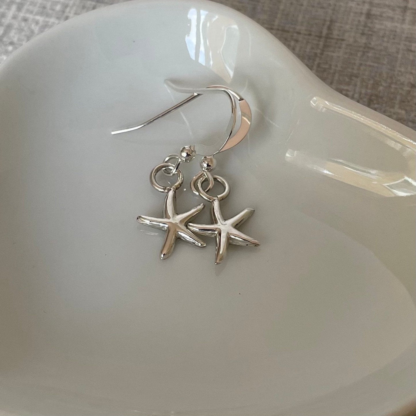 Close-up of handmade sterling silver starfish earrings, showcasing the intricate design and recycled sterling silver craftsmanship