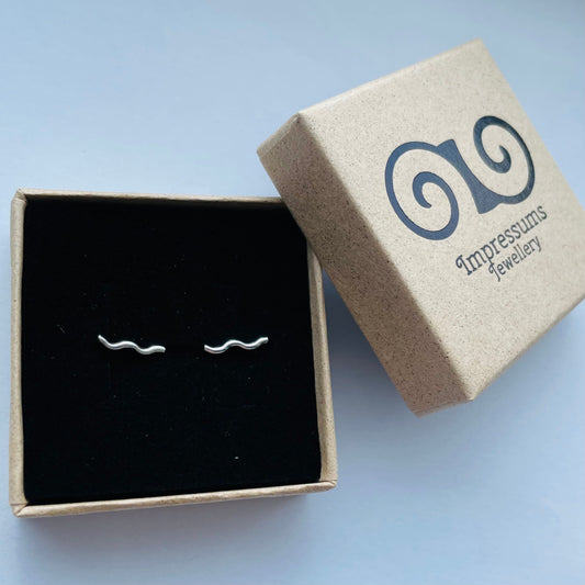 A pair of sterling silver squiggle bar stud earrings in an Impressums Jewellery branded gift box, ready for gifting.