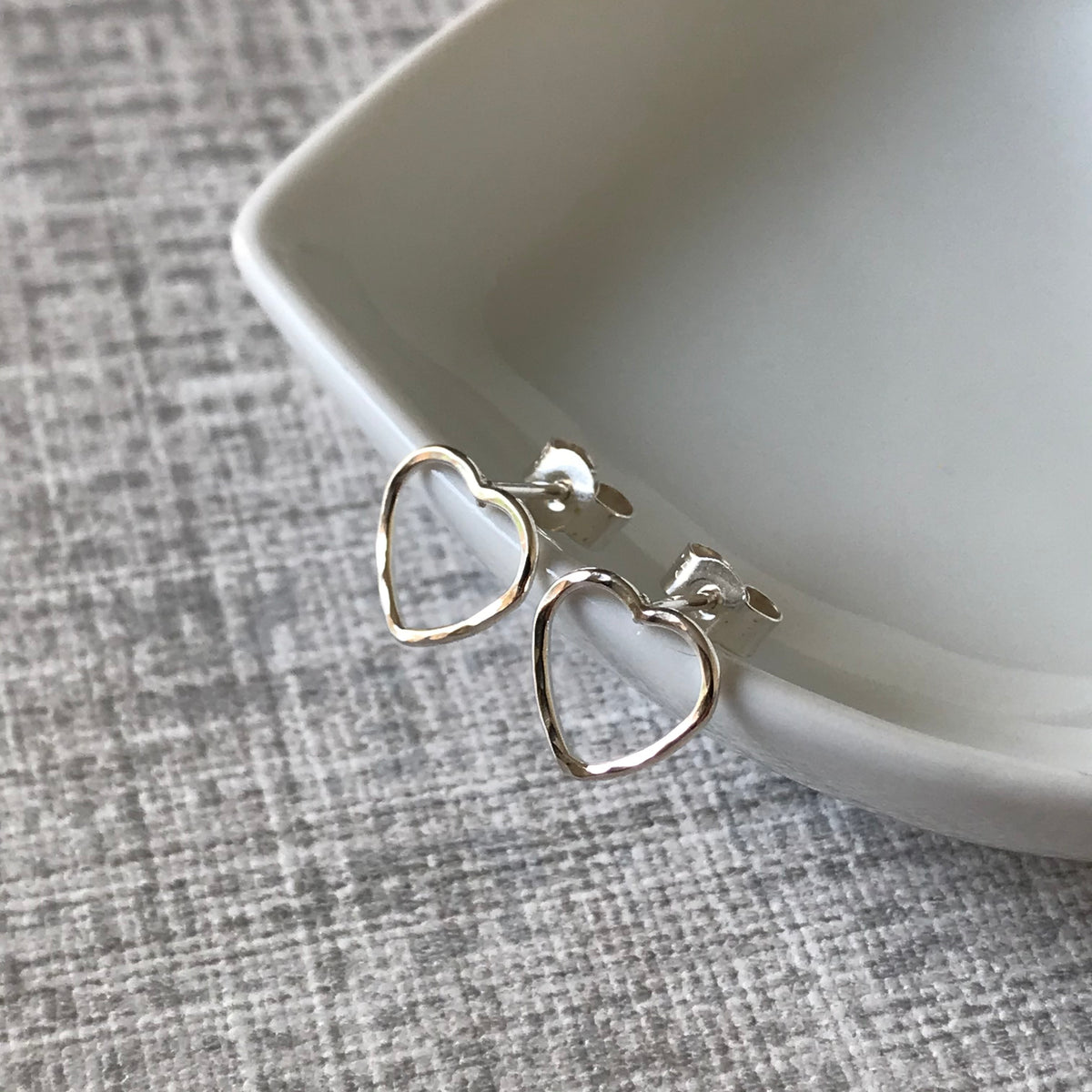 Handmade sterling silver heart stud earrings with a hammered texture