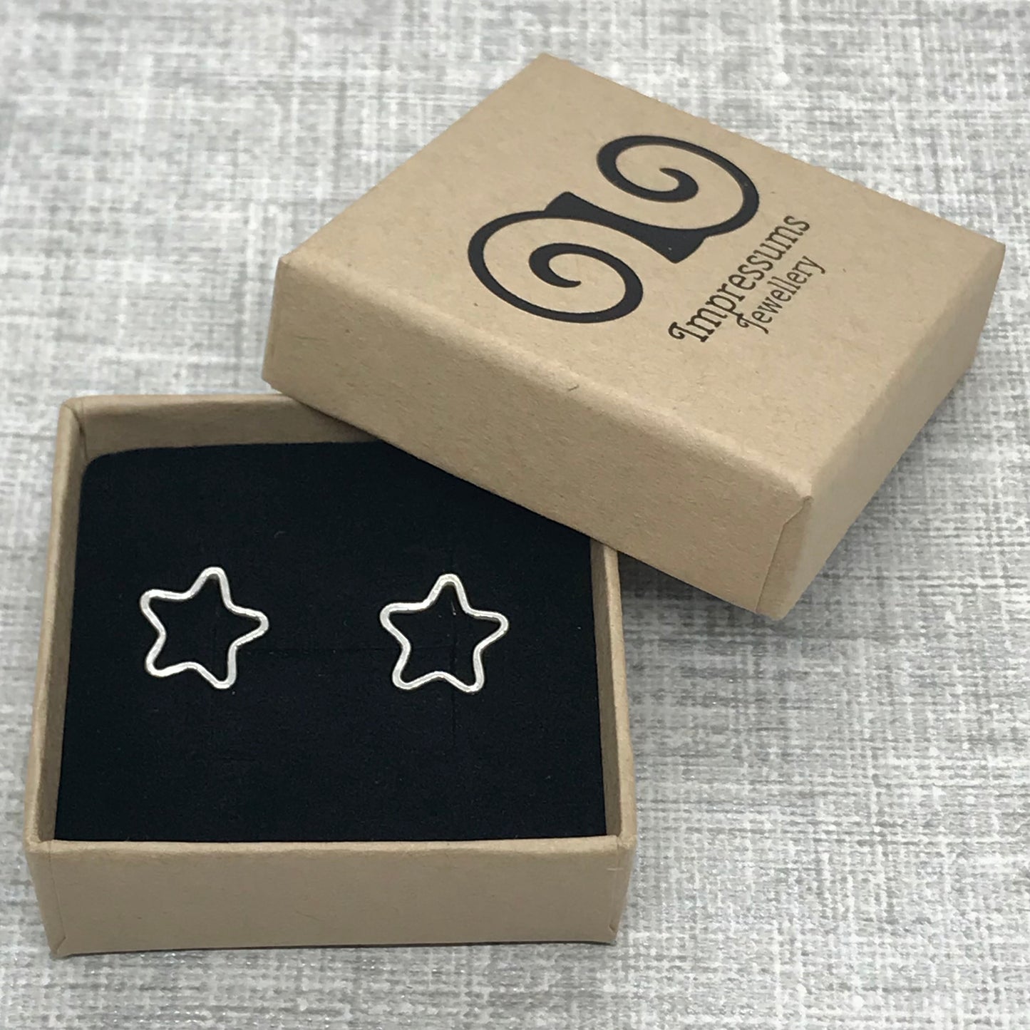 A pair of sterling silver open star earrings in an Impressums Jewellery branded gift box, ready for gifting
