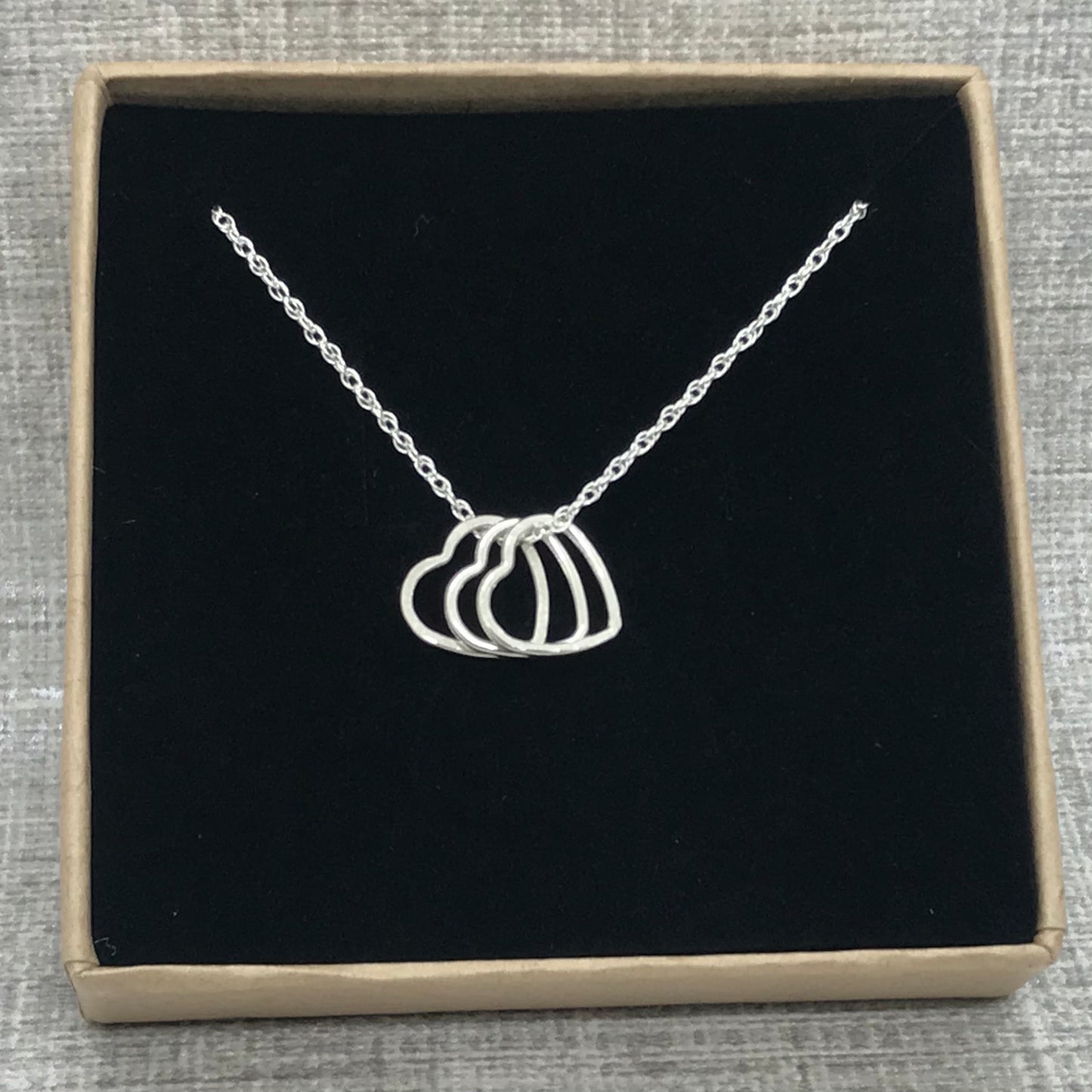 A sterling silver heart charm necklace in an Impressums Jewellery branded gift box, ready for gifting.