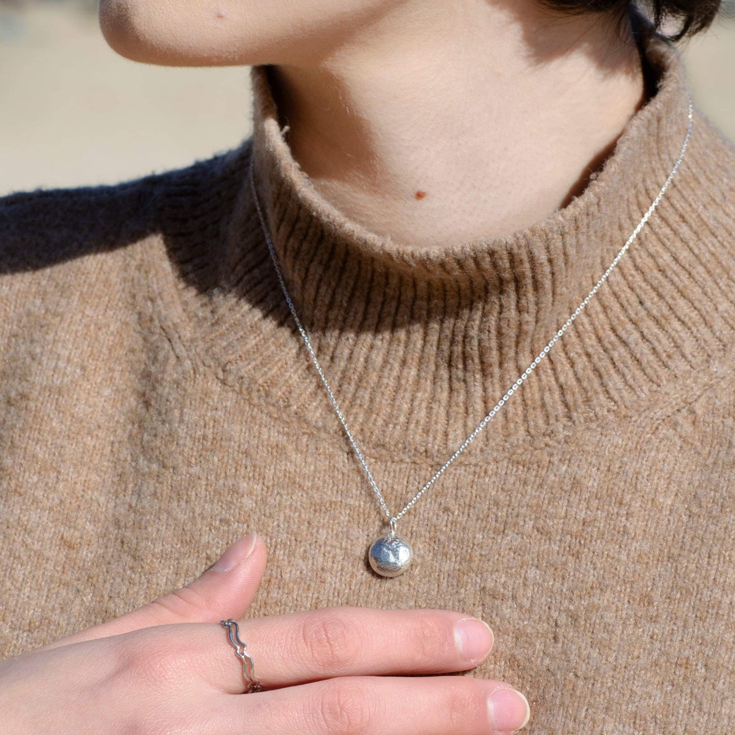 A model wearing the sterling silver pebble necklace, showcasing its minimalist and contemporary design.