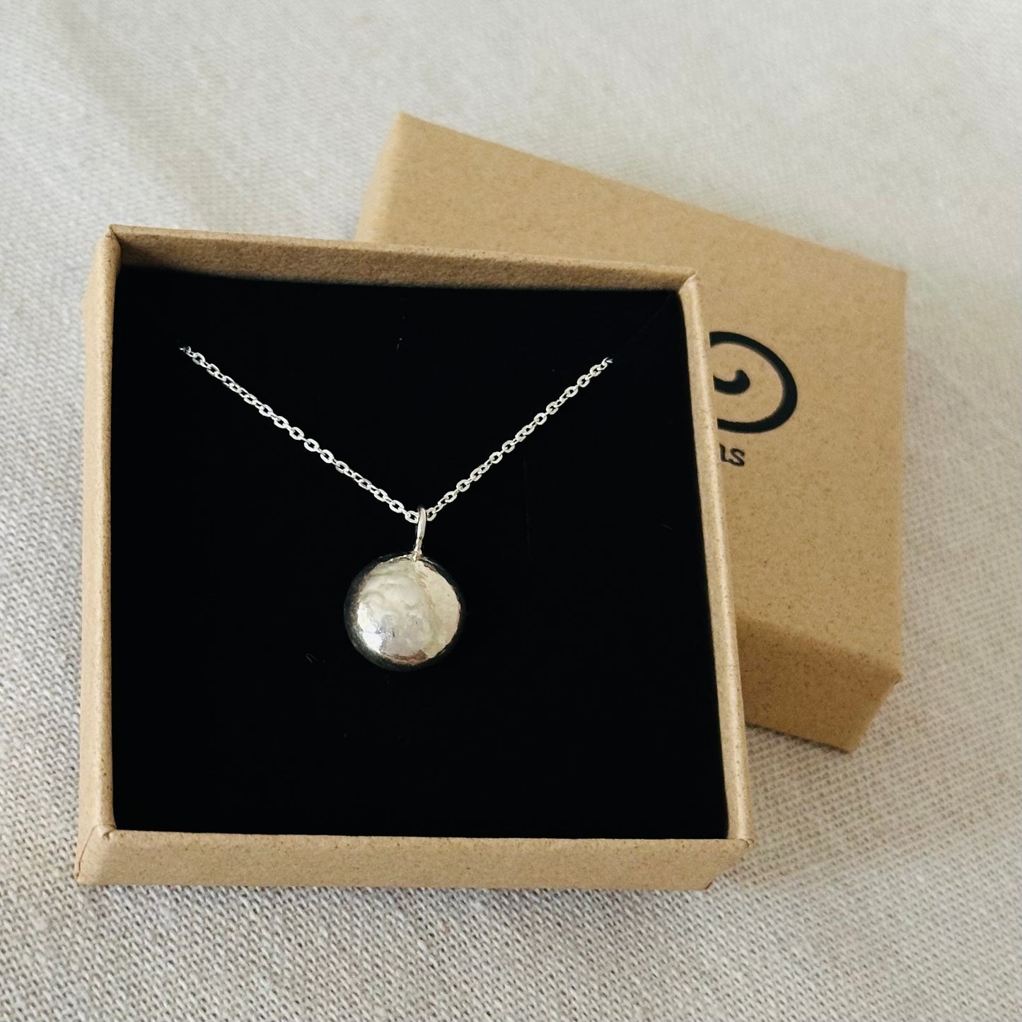 A sterling silver pebble pendant in an Impressums Jewellery branded gift box, ready for gifting.