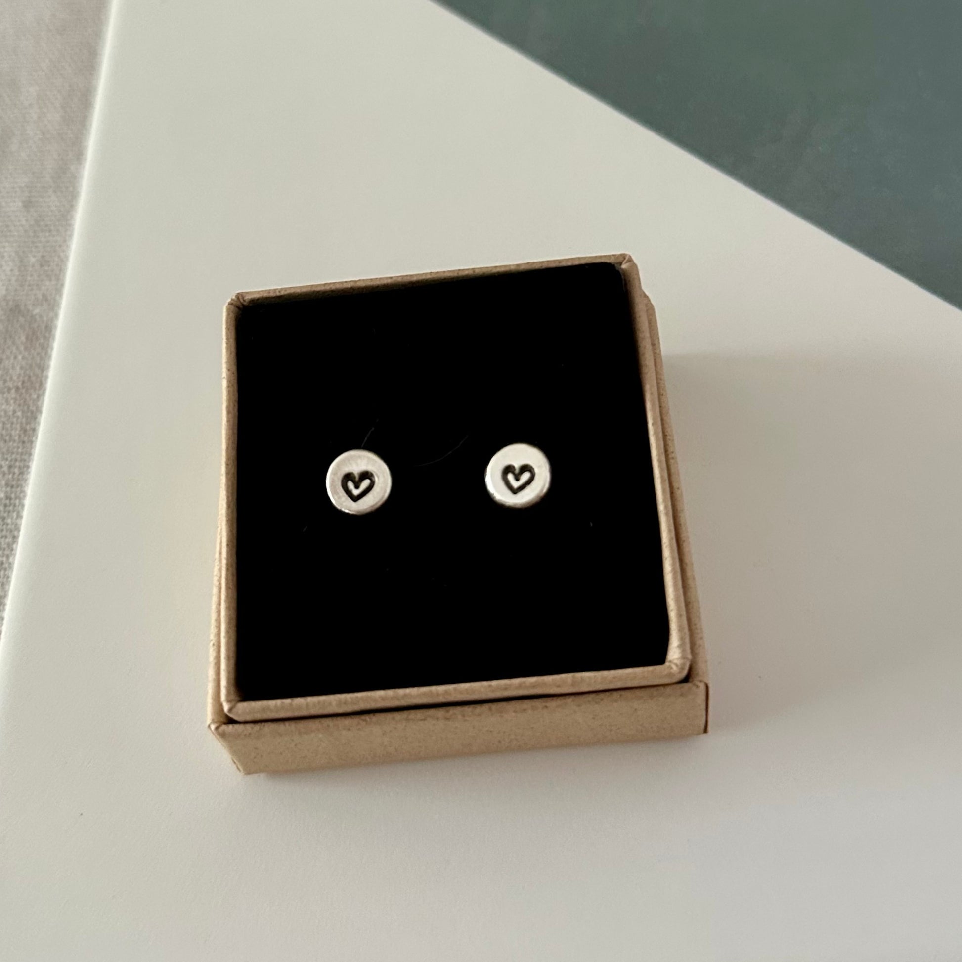 Pair of unique, eco-friendly sterling silver sweetheart studs displayed on a plain background, highlighting artisanal details.