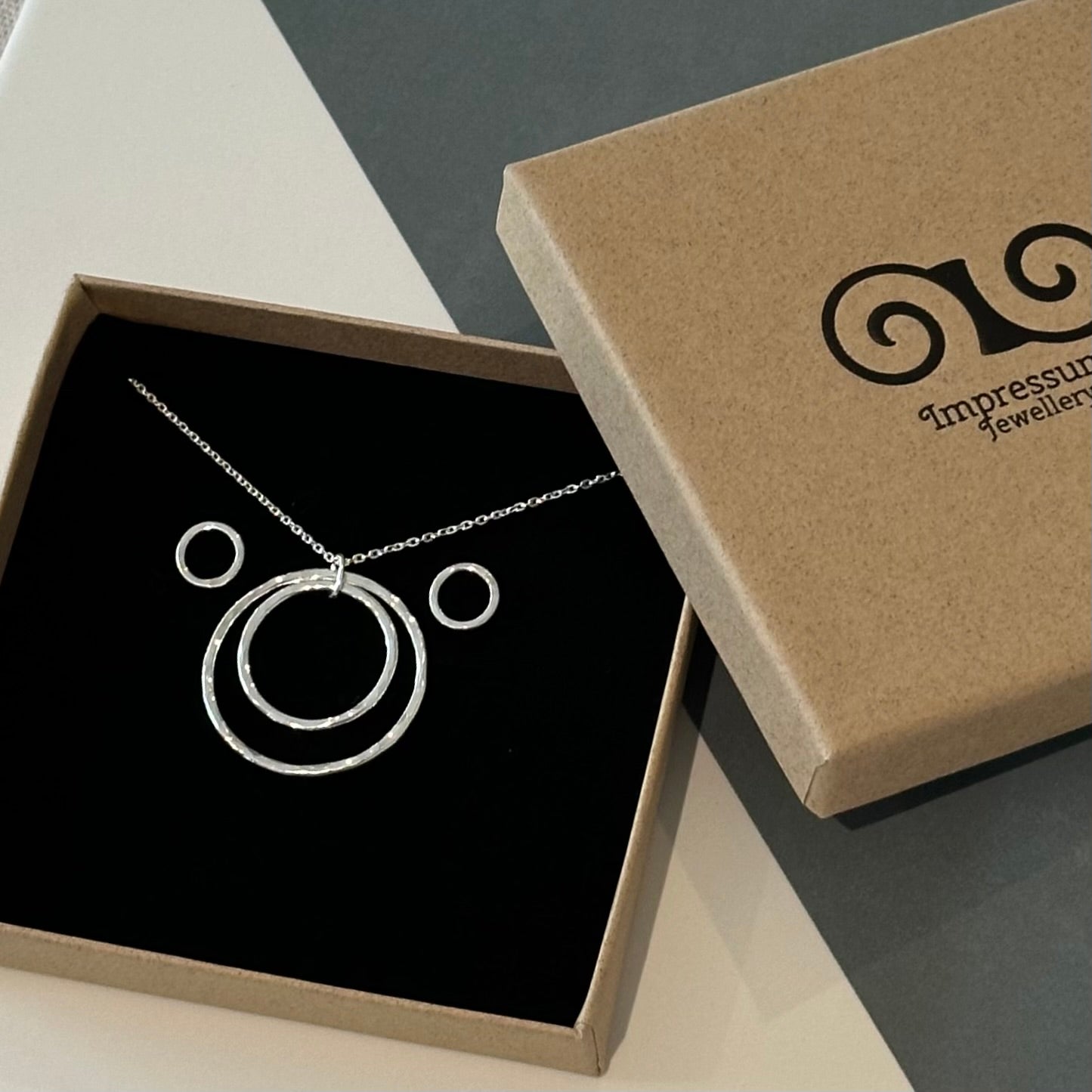 Handmade recycled sterling silver double circle pendant and stud earring set, displayed in a branded gift box.