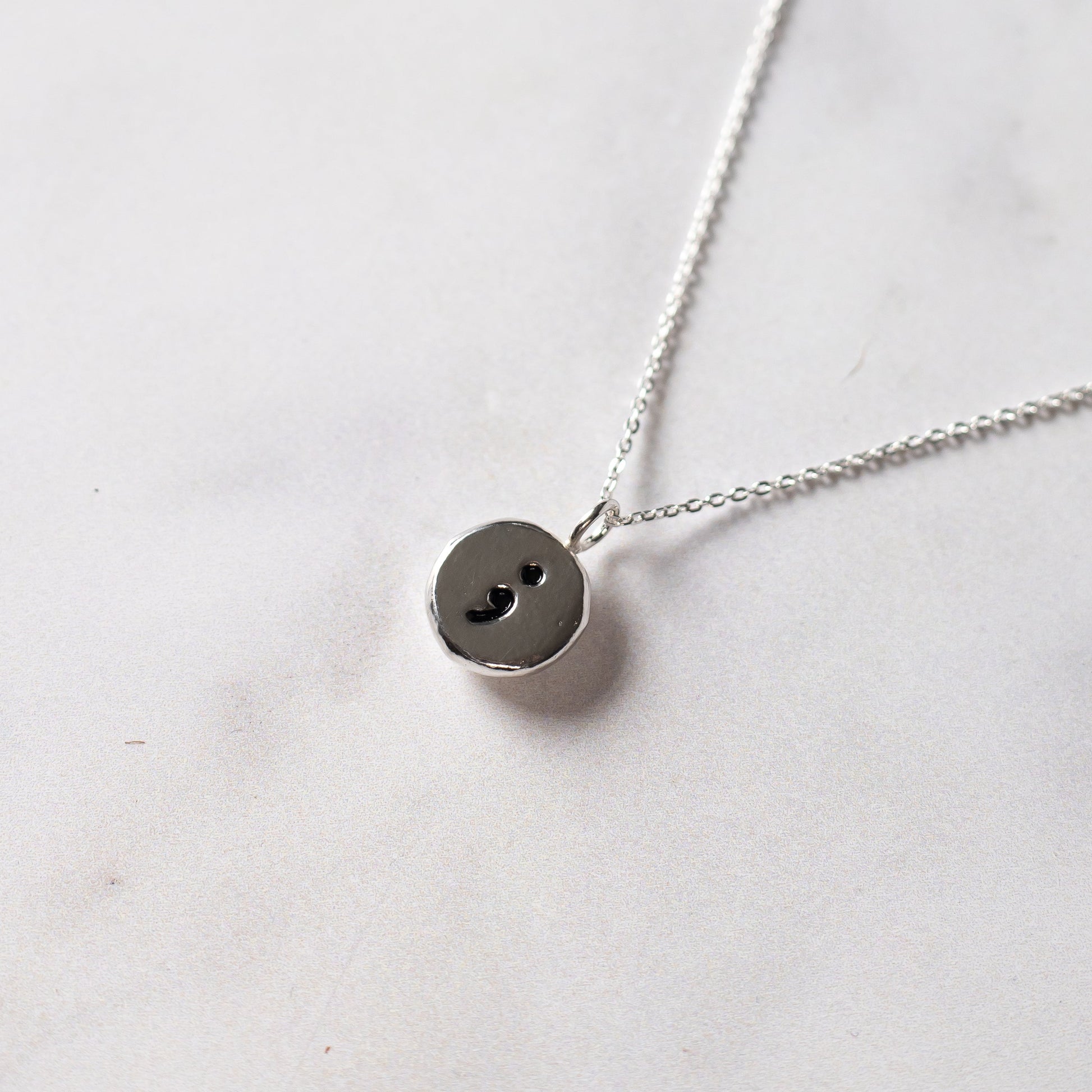 Silver necklace with a round pendant on a white background