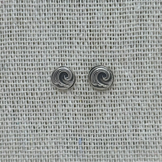 Close-up of the silver wave pebble earrings, highlighting the embossed details and patinated finish.