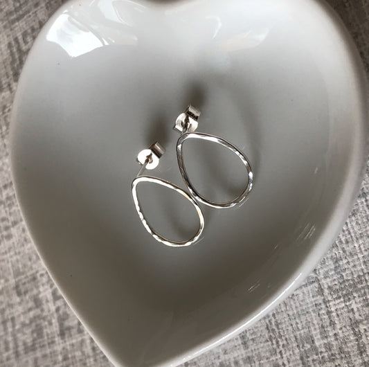 Close-up of silver teardrop earrings showing the unique hand-hammered texture that catches the light