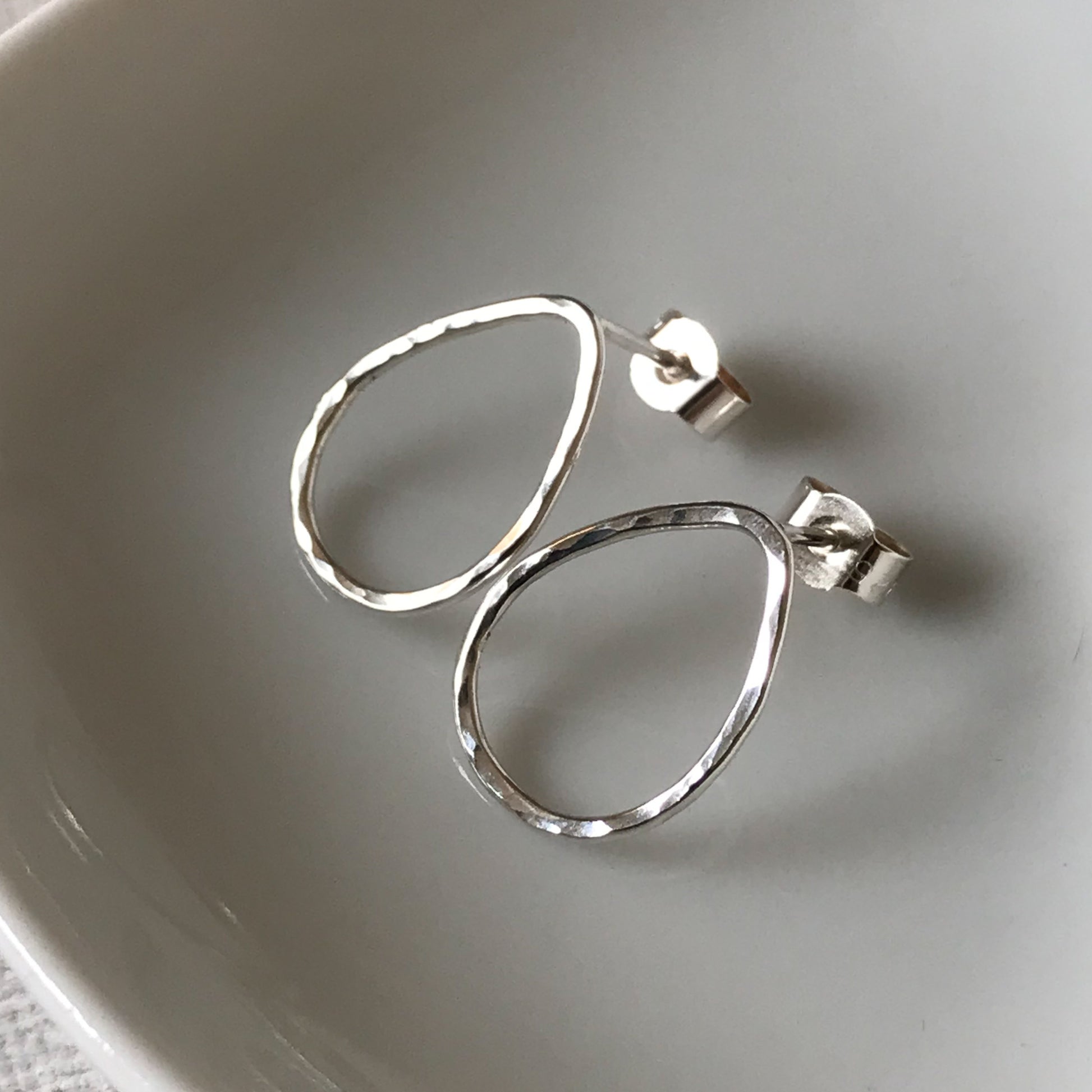 Handmade sterling silver teardrop stud earrings with a hammered texture, displayed against a white background.