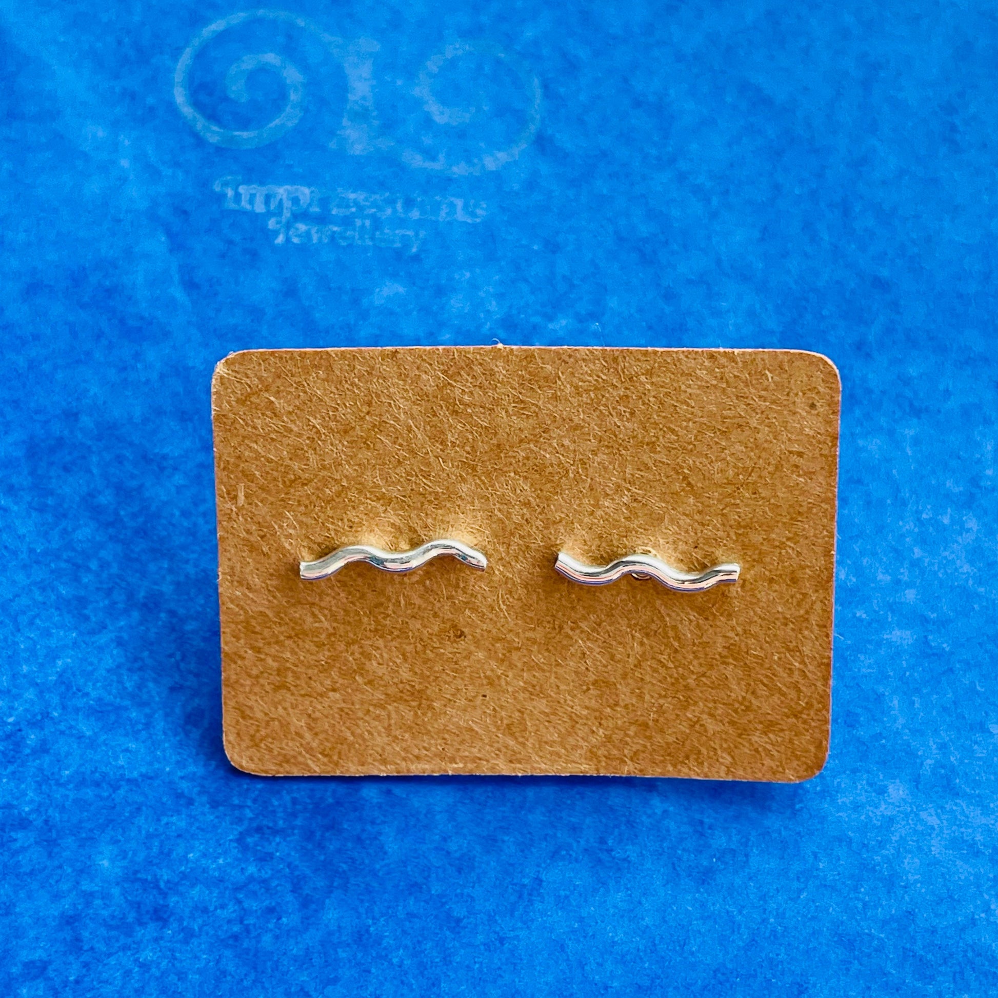 Close-up of the silver wavy bar earrings, highlighting their smooth, organic curves and polished finish.