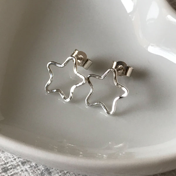 Handmade hammered sterling silver open star stud earrings, displayed against a white background