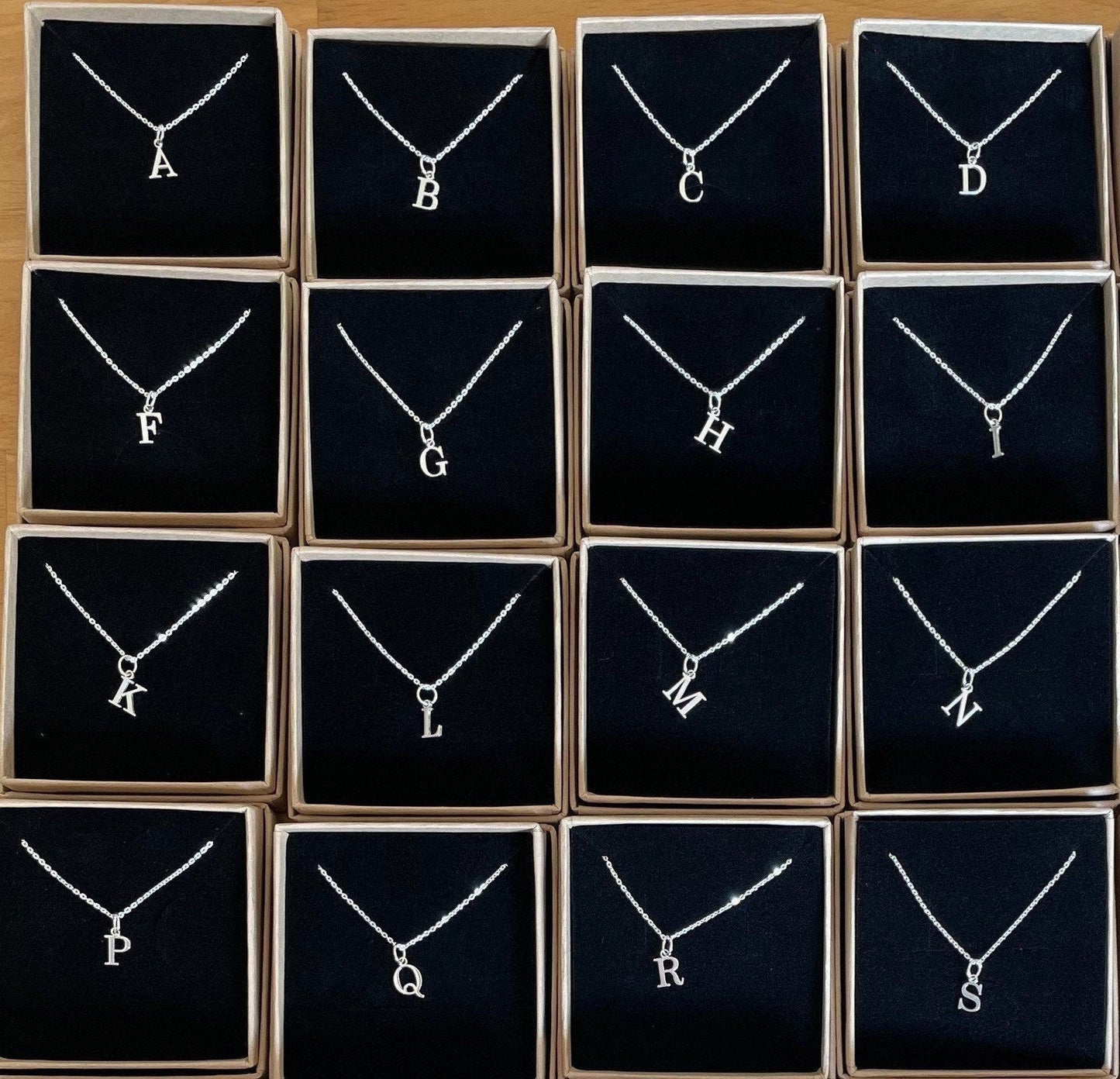 A sterling silver initial necklace in an Impressums Jewellery branded gift box, ready for gifting.