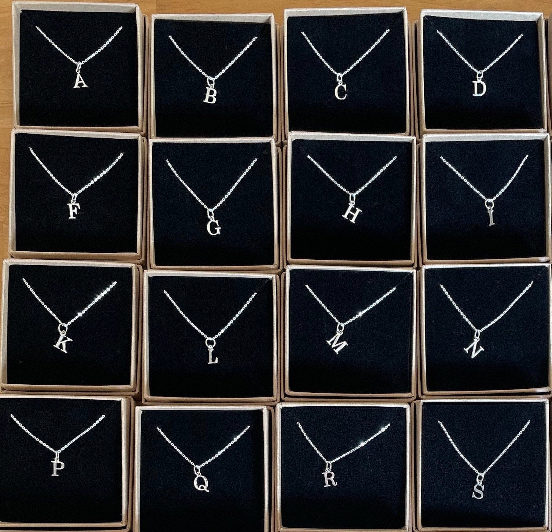 A sterling silver initial necklace in an Impressums Jewellery branded gift box, ready for gifting.