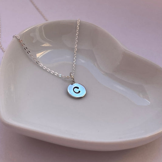 Close-up of the silver initial pendant, showcasing the hand-stamped custom letter and polished finish