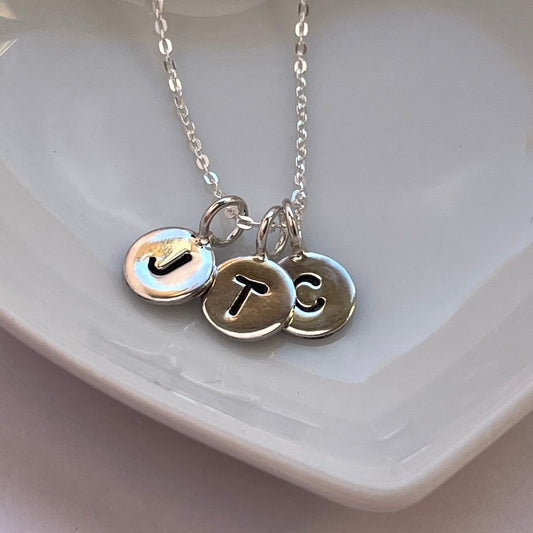 Handmade sterling silver initial necklace featuring an 8mm disc stamped with a single capital letter, displayed on an 18-inch silver trace chain.