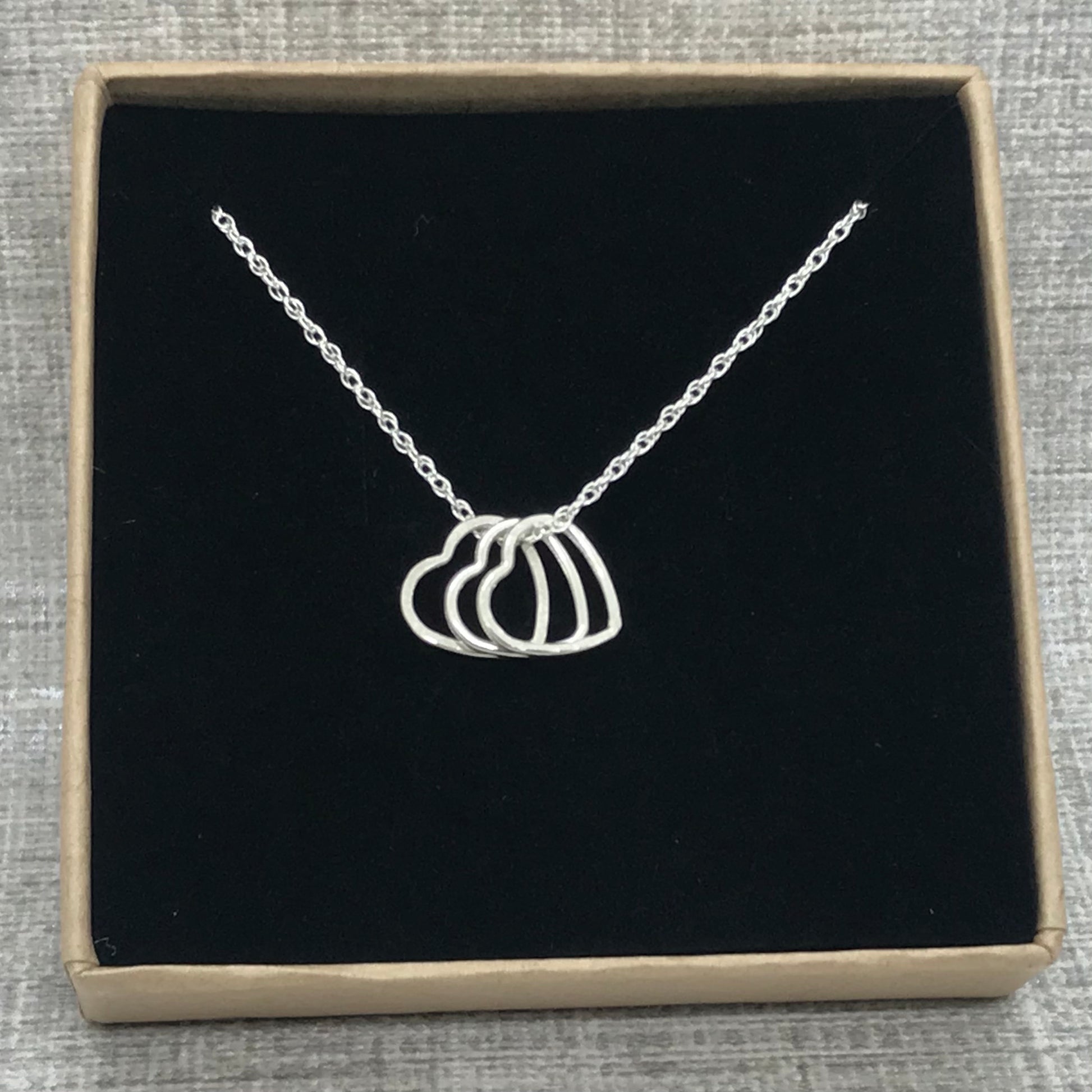A sterling silver heart charm necklace in an Impressums Jewellery branded gift box, ready for gifting.