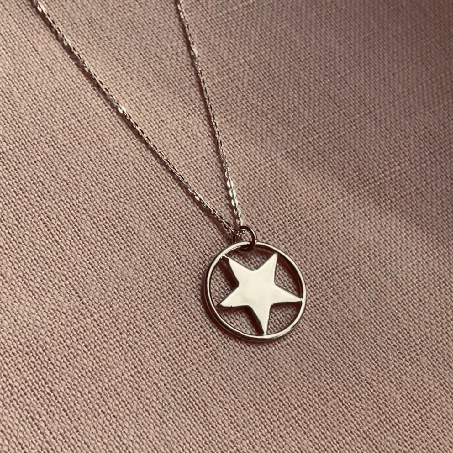 Handmade sterling silver star pendant necklace, featuring a five-pointed star set within a circular frame, displayed on an 18-inch silver trace chain.