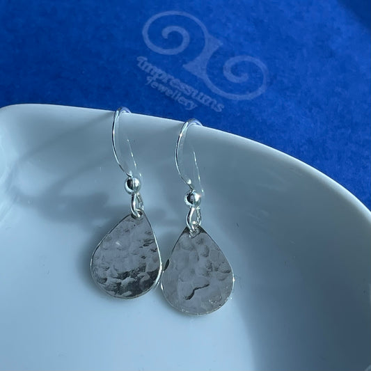 Close-up of the silver teardrop earrings, highlighting the hammered finish and organic handcrafted texture.