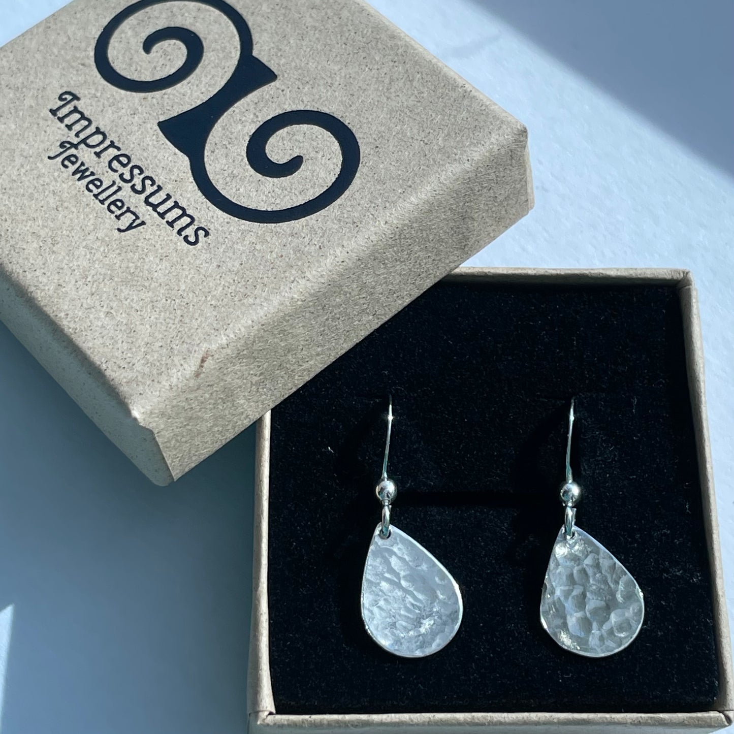 A sterling silver teardrop dangle earrings in an Impressums Jewellery branded gift box, ready for gifting.