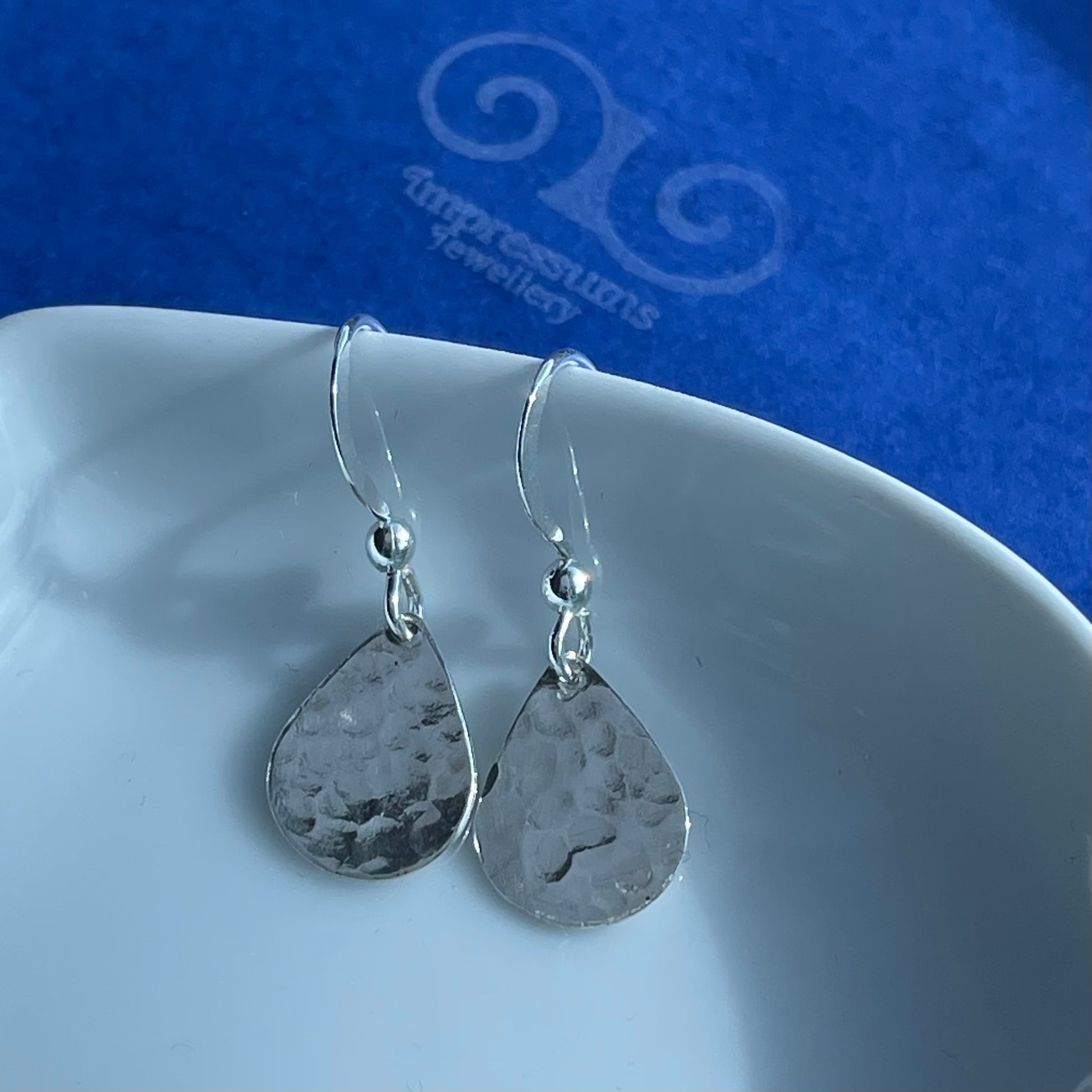 Close-up of the silver teardrop earrings, highlighting the hammered finish and organic handcrafted texture.